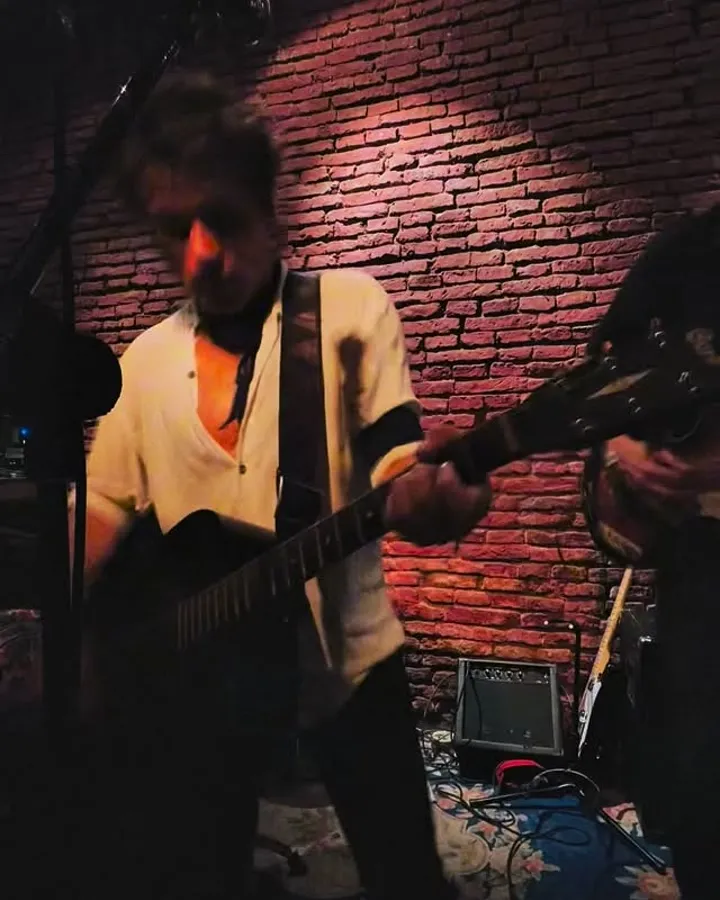 Guitarrista contra una pared de ladrillo, en vivo
